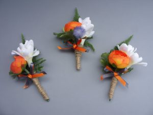 Buttonhole - Orange Ranunculus, Tuberose, backed with Asparagus Fern. Decorated with twine and orange & grey ribbon bow - from £6.00 each