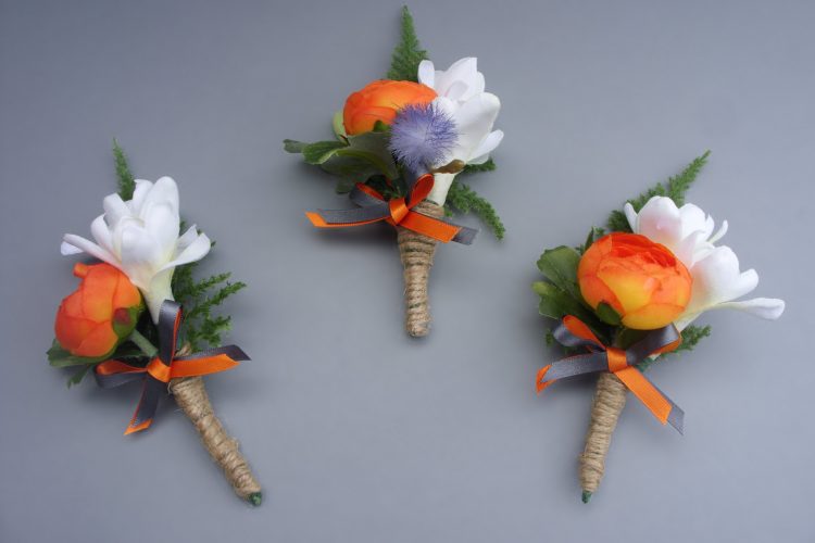 Buttonhole - Orange Ranunculus, Tuberose, backed with Asparagus Fern. Decorated with twine and orange & grey ribbon bow - from £6.00 each