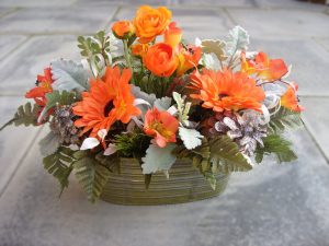 Graveside Arrangement - Orange Runucular, Astromeria and Orange Gerbera, in a Jorvik tin trough with Leather Leaf and Dusty Miller foliage - £42.00