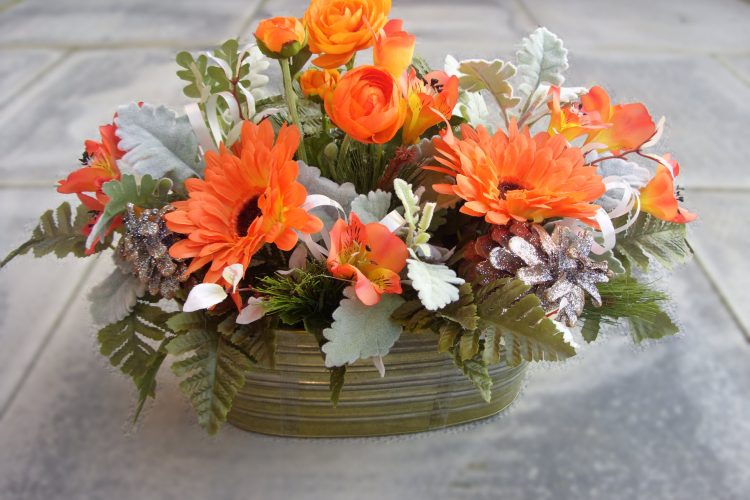 Graveside Arrangement - Orange Runucular, Astromeria and Orange Gerbera, in a Jorvik tin trough with Leather Leaf and Dusty Miller foliage - £42.00